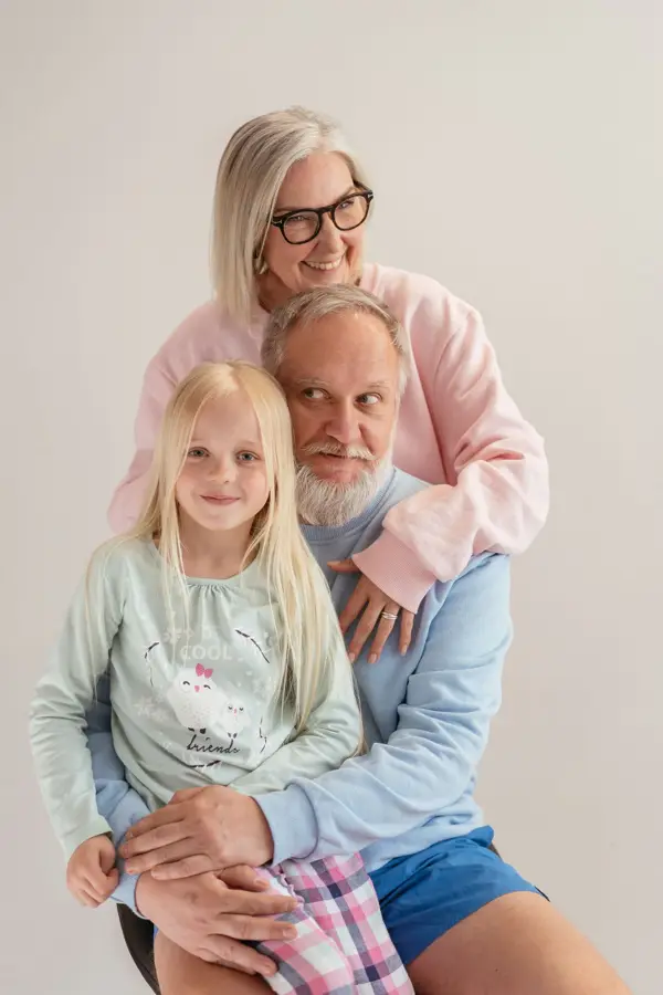Grandparents hugging their granddaughter